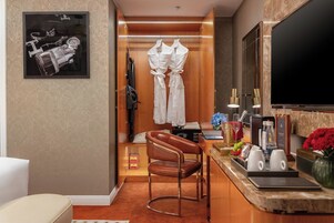 A hotel room with a bed, a desk with a computer, a chair, and a TV.