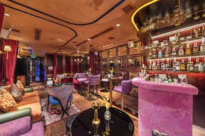 A bar area with a pink bar counter, multiple seating options including purple chairs, and a variety of liquor bottles. - The Haron Hanoi Boutique Hotel (Hanoi)