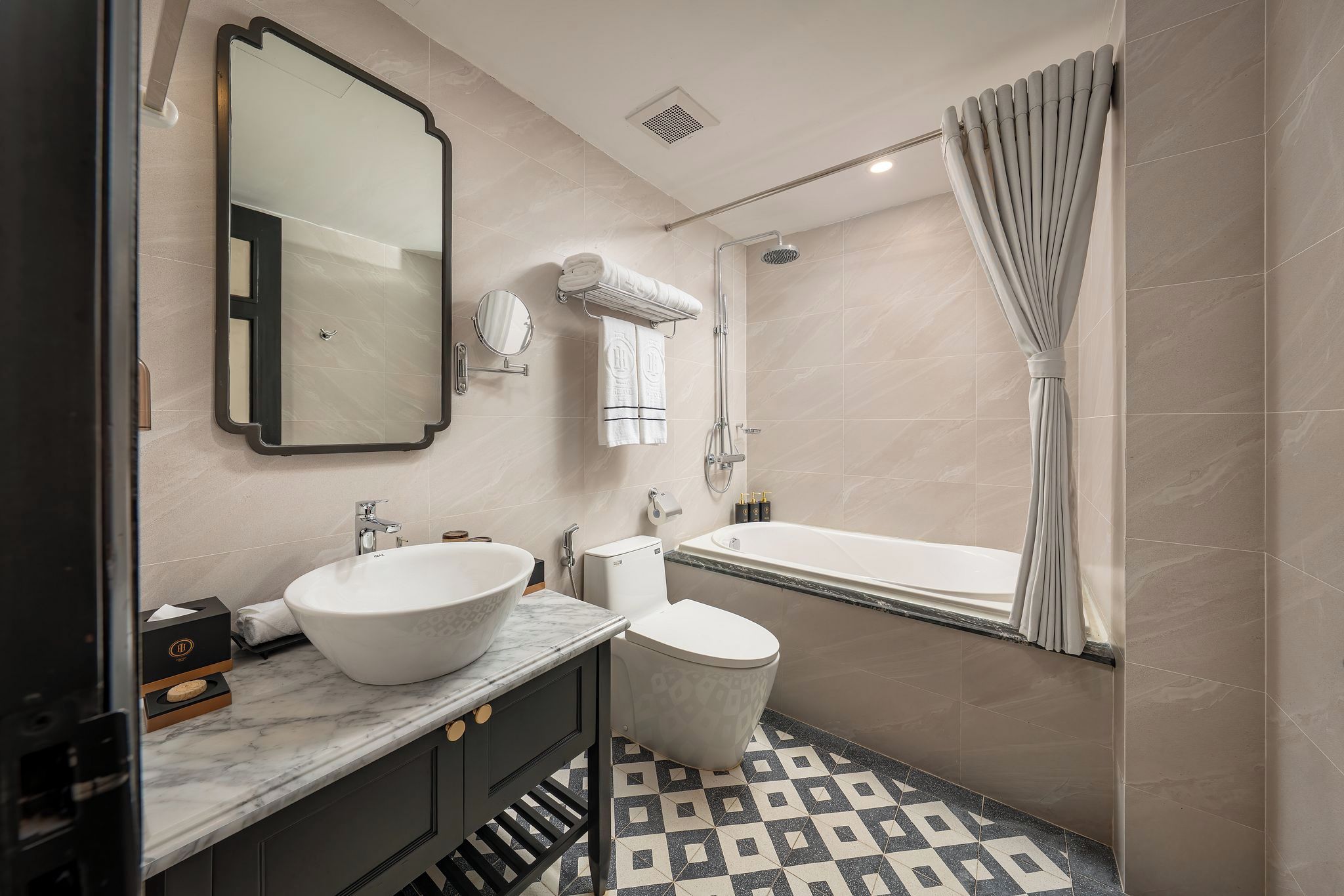 A modern bathroom with a large mirror, a vessel sink, a toilet, and a bathtub.