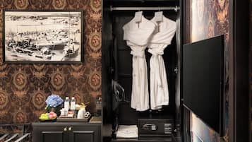A hotel room with a vintage photo, a robe, toiletries, and a minibar.