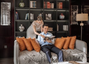 A modern living room with a sofa, cushions, a bookshelf, and a lamp. - The Haron Hanoi Boutique Hotel (Hanoi)