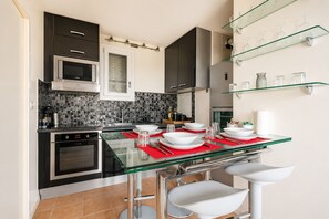 Uma cozinha moderna com mesa de jantar de vidro, eletrodomésticos de aço inoxidável e painel de azulejos.