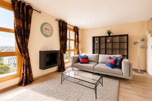 Uma sala de estar com sofá, mesa de centro, televisão e estante de livros.