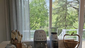 Una encimera de cocina con dos cafeteras, un tostador y un juego de cuchillos.