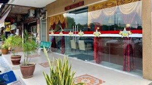 A storefront with a glass facade, potted plants, and a sign indicating a business. - Royals Star Hotel (Seremban)