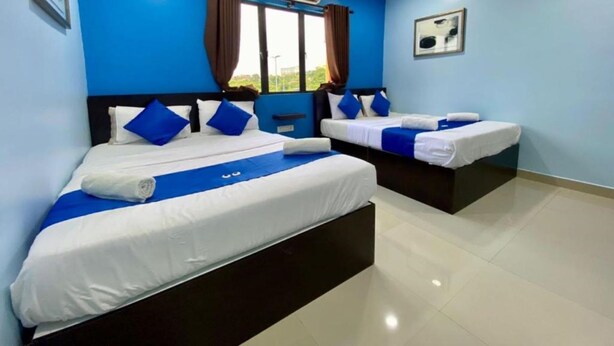 A hotel room with two beds, blue walls, and an air conditioning unit. - Royals Star Hotel (Seremban)