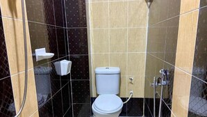 A small bathroom with a toilet, a shower, and a towel rack. - Royals Star Hotel (Seremban)