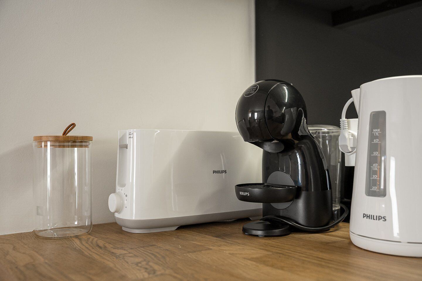 A kitchen counter with a Philips toaster, a Philips coffee maker, and a clear glass jar with a wooden lid.