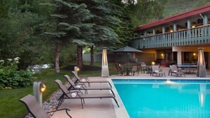 A pool area with lounge chairs and a building with a balcony. - Convenient 2BR Condo Near Lionshead Village With Resort Amenities (Vail)