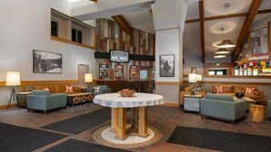 A hotel lobby with a central round table, seating areas with sofas, a bar area, and framed pictures on the walls. - Convenient 2BR Condo Near Lionshead Village With Resort Amenities (Vail)
