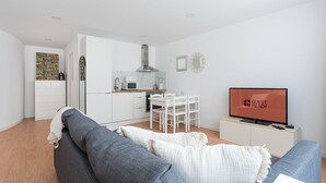 A modern apartment with a living room, kitchenette, and a TV displaying "GUEST READY".