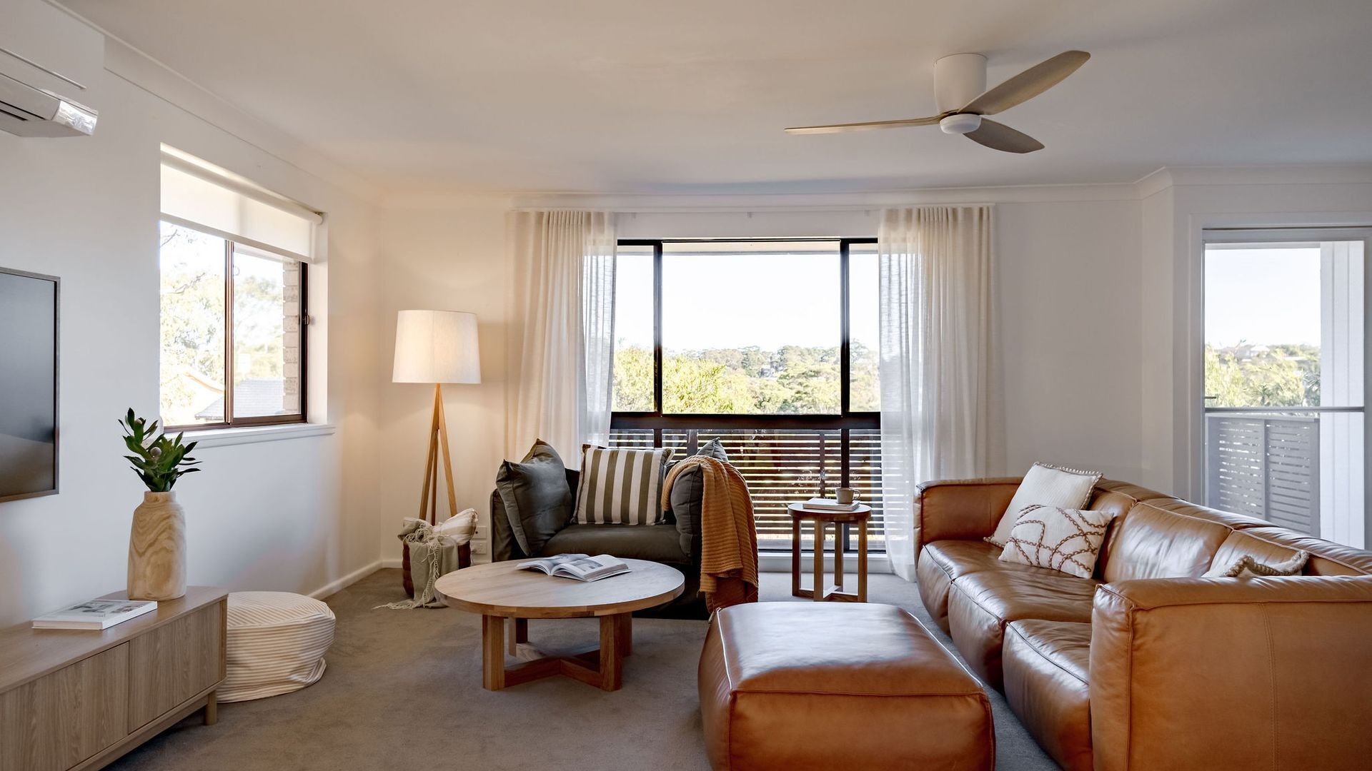 Un salon moderne avec un canapé, une table basse, un lampadaire et un téléviseur posé sur un meuble.