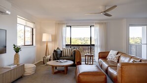 A modern living room with a sofa, a coffee table, a floor lamp, and a TV on a stand.