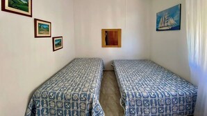 A room with two single beds, a ceiling fan, and three framed pictures on the wall. - A Beachfront Oasis, 220m (Guarujá)
