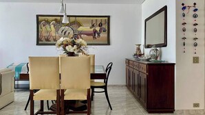 A dining area with a table and chairs, a vase of flowers, and a painting on the wall. - A Beachfront Oasis, 220m (Guarujá)