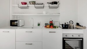 A modern kitchen with white cabinetry, a microwave, a stove, and various kitchen utensils. - Nova Lake View - Apartment with Balcony in Stresa, Stresa, Italy (Stresa)