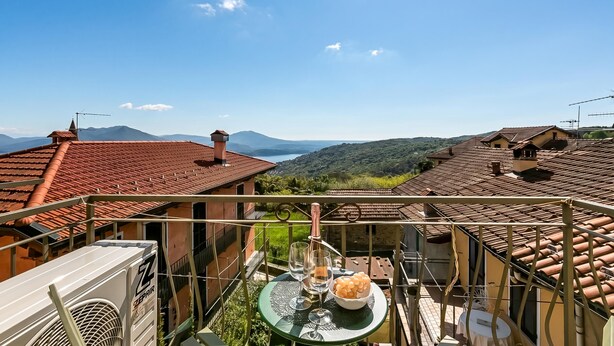 A balcony with a table set for two, overlooking a mountainous landscape. - Nova Lake View - Apartment with Balcony in Stresa, Stresa, Italy (Stresa)