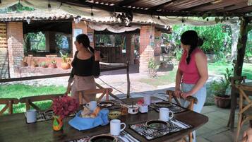 Un patio al aire libre con zona de comedor cubierta, paredes de ladrillo y plantas en macetas.