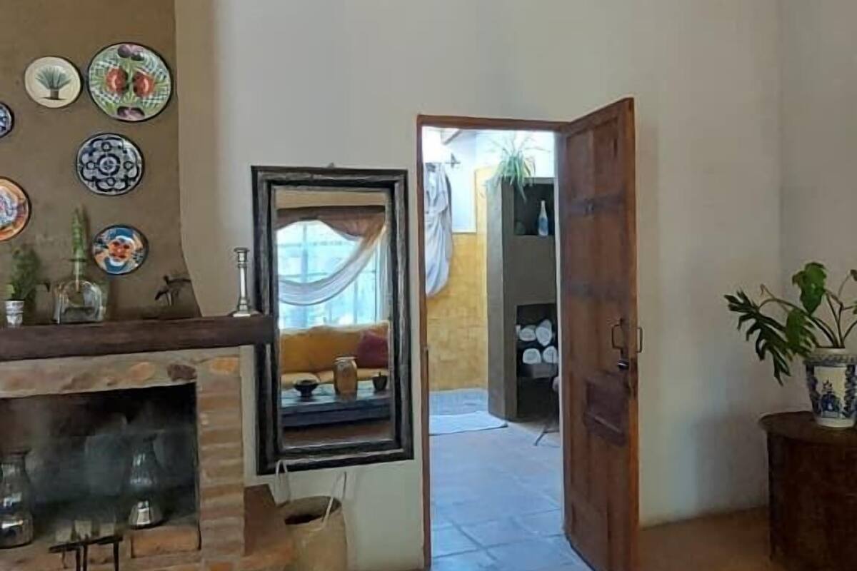 Ein rustikaler Innenraum mit unverputzten Backsteinwänden, einem Kamin und einer Holzbalkendecke.
