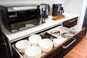 Een koelkast, een magnetron, een kookplaat, kookgerei, borden en bestek