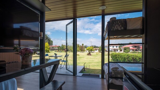 Een modern interieur met een grote glazen deur die uitkomt op een tuin, een bank en een eethoek met tuinmeubels.