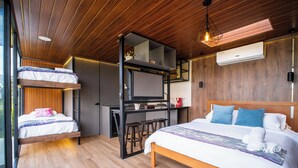 Een moderne kamer met een stapelbed, een bureau en een groot bed met kussens.