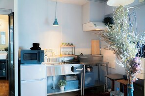 Een koelkast, een magnetron, een kookplaat, kookgerei, borden en bestek