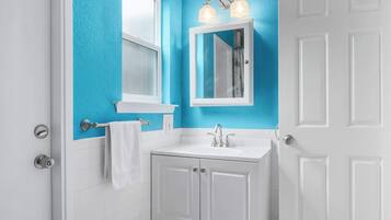 A bathroom with a white vanity, a blue accent wall, and a white door.