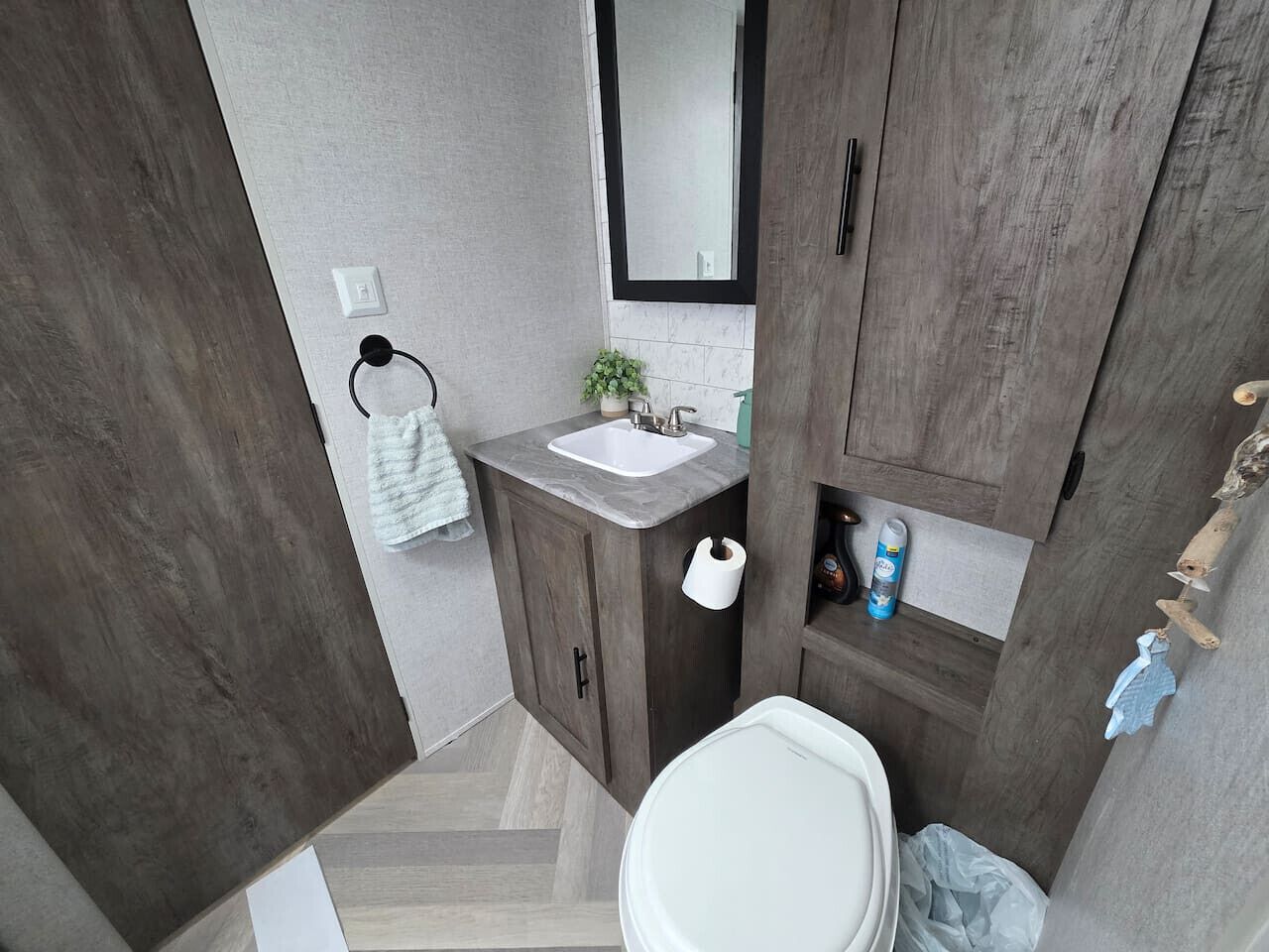 Een moderne badkamer met een houten wastafel, een witte wasbak en een spiegel erboven.