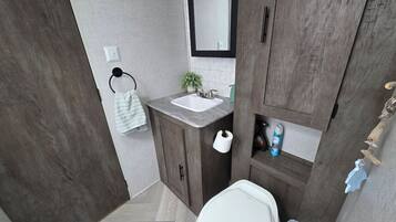 Een moderne badkamer met een houten wastafel, een witte wasbak en een spiegel erboven.