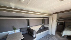 Ein kompakter Wohnbereich mit einer Couch, einem kleinen Tisch und einem Bett.
