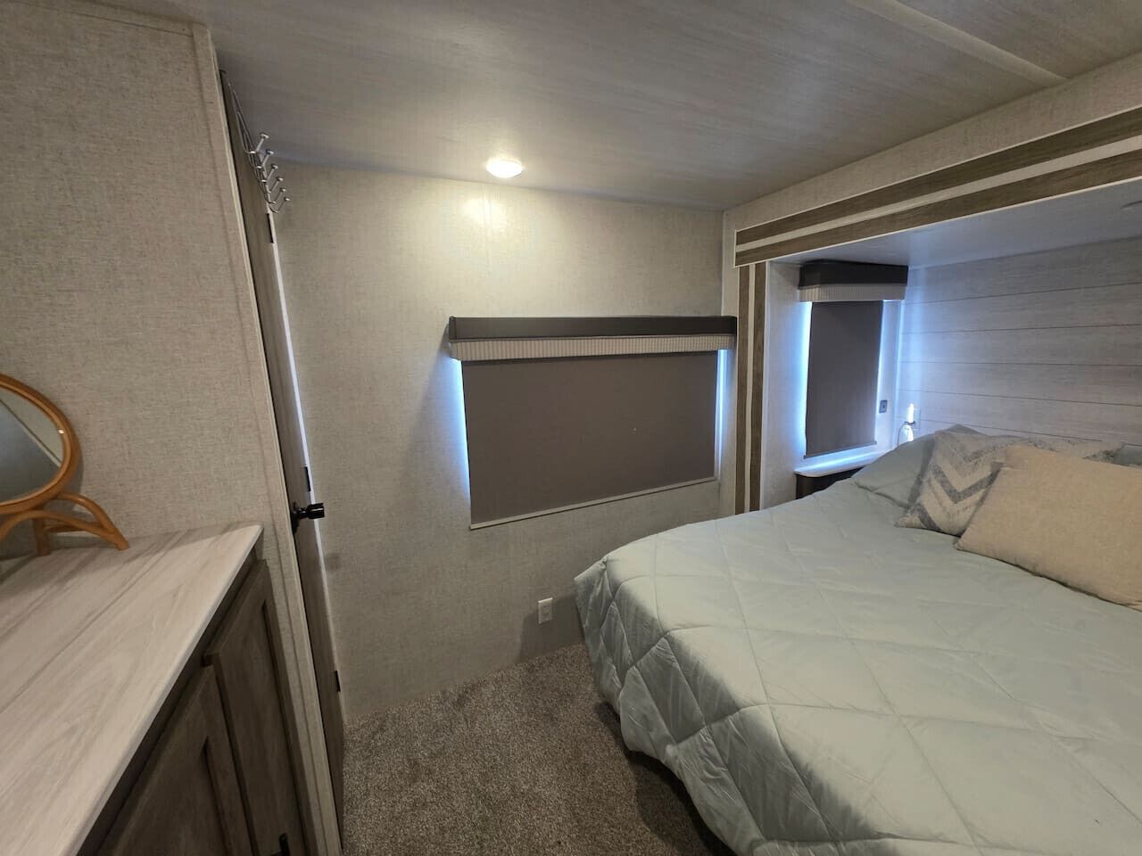 Une chambre à coucher avec un lit, une fenêtre, un miroir et une petite table.