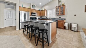 A spacious kitchen with a central island, wooden cabinets, stainless steel appliances, and a large window.
