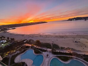 A resort with multiple swimming pools, a beach, and a sunset view. - Costa Herradura (Coquimbo)