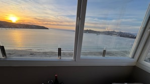 A balcony with a view of the sea at sunset, a table with bottles and glasses, and a bench. - Costa Herradura (Coquimbo)