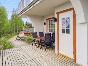 A wooden deck with a table and chairs, a white door, and a view of a forested area. - Mukalilla, paritalo sis loppusiivouksen by Interhome (Hyrynsalmi)