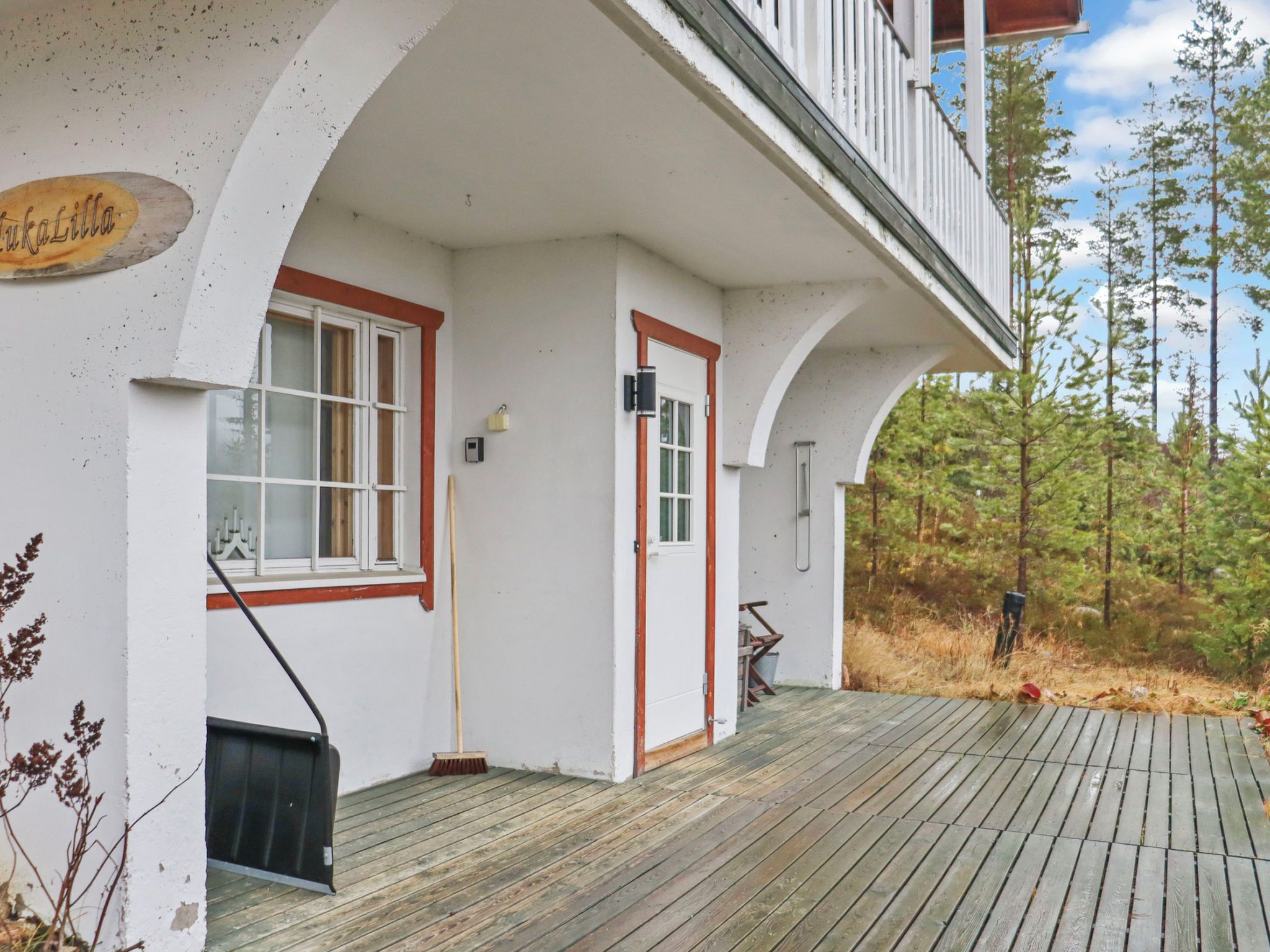 A building with a white exterior, a wooden deck, and a sign that reads 'TukaLilla'.