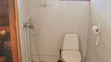 Un baño pequeño con inodoro, ducha y soporte para papel higiénico.