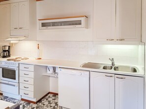A kitchen with white cabinets, a built-in oven, a coffee maker, and a sink with a modern faucet. - Mukalilla, paritalo sis loppusiivouksen by Interhome (Hyrynsalmi)