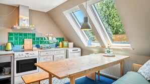 A kitchen with a wooden table, a stove, and a window with a view of greenery.