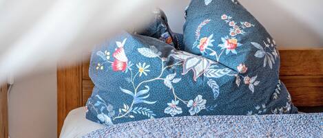 A bed with a floral-patterned pillow and a blue blanket.
