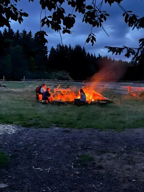 En gruppe mennesker samlet omkring et bål i det fri.