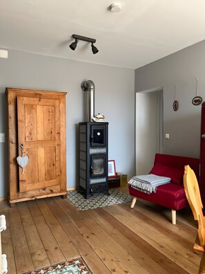 A room with a wooden door, a black wood stove, a red sofa, and a wooden floor. - Apartment 'Rotkäppchen' with Shared Garden and Wi-Fi (Eisenbach (Hochschwarzwald))