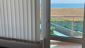 Une pièce avec vue sur un balcon, une fenêtre avec des stores et un sol carrelé.