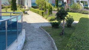 Un immeuble moderne à plusieurs étages, doté de balcons, d’une piscine et de jardins bien entretenus.