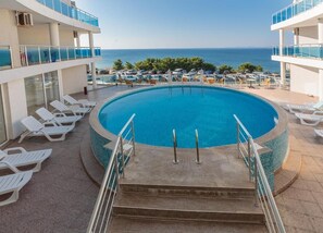 Ett poolområde med fri utsikt över havet, omgivet av solstolar och en poolterrass.