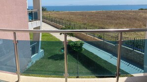 Un balcon avec vue sur la mer et un espace verdoyant.
