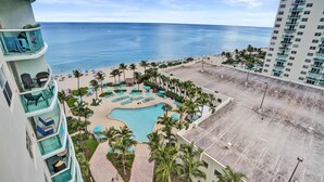 A resort with a pool, palm trees, and a view of the ocean. - Beachfront Getaway | Direct Ocean Views + Balcony (Hollywood)