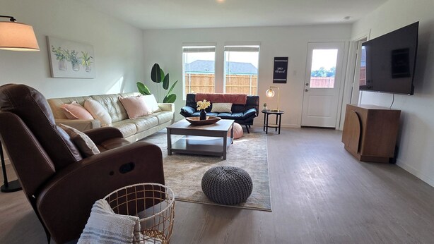 A living room with a sofa, a coffee table, a TV, and a lamp. - Cute Brand New Home in McKinney (McKinney)