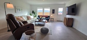 Un salon avec un canapé, une table basse, un téléviseur et une lampe.
